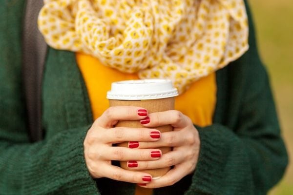 woman holding coffee cup; small inexpensive gifts for employees