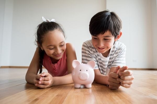 two kids looking at a piggy bank; budget for kids