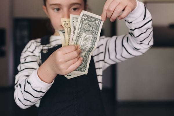 girl holding money; budgeting worksheet printable free