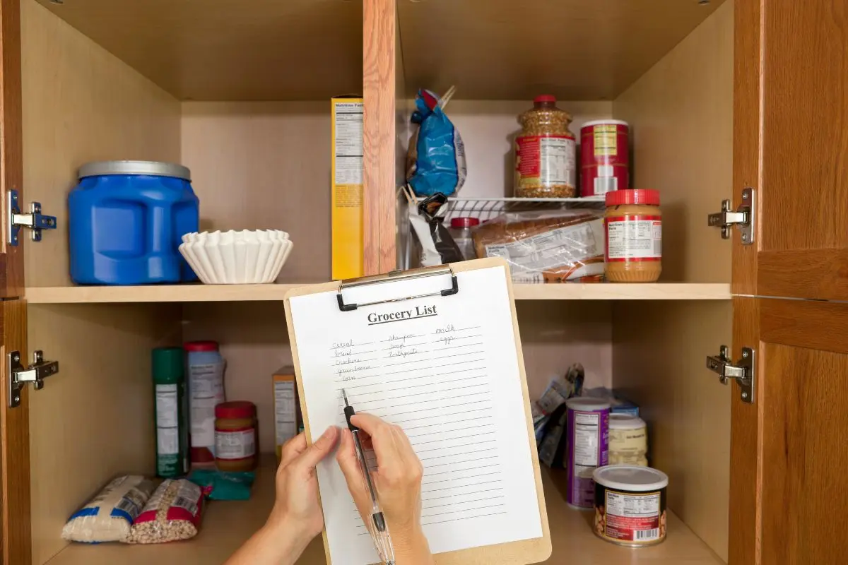 looking in open pantry and making a grocery list