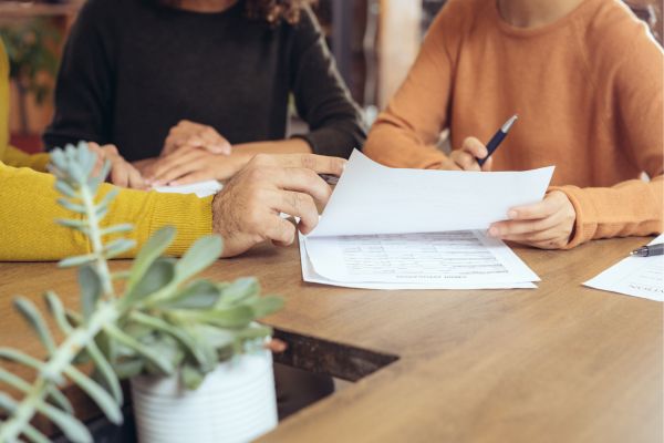 three people sitting at a table looking at papers; how can a kid make money