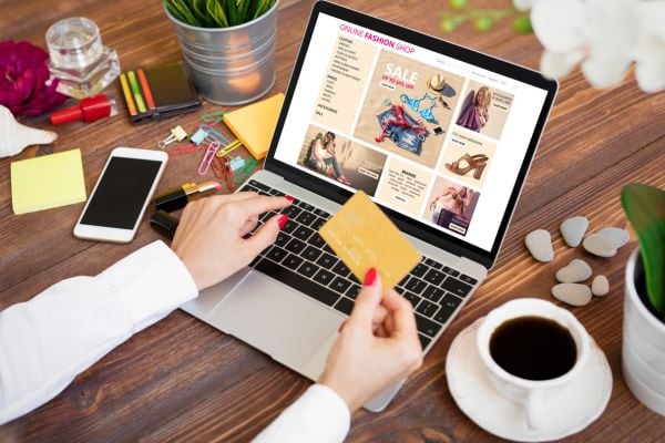 woman looking at website with credit card in hand; how to stop online shopping and buying clothes