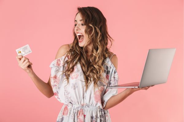 woman holding computer and credit card with mouth open; how to stop online shopping and buying stuff